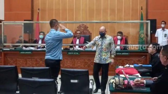 Ajudan Irjen Teddy Minahasa, Arif Hadi Prabowo, memberikan hormat kepada Teddy Minahasa usai memberikan kesaksian di Pengadilan Negeri Jakarta Barat, Senin (13/2/2022). (Suara.com/ Faqih Faturrachman)