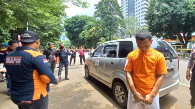 Anggota Densus Bripda HS alias Haris Sitanggang (baju tahanan) saat menjalani rekonstruksi kasus pembunuhan sopir taksi online di Depok. (Suara.com/M Yasir)