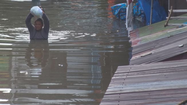 Warga membawa barang dari rumahnya yang terendam banjir di Pucang Sawit, Solo, Jawa Tengah, Jumat (17/2/2023).  [ANTARAFOTO/Maulana Surya].