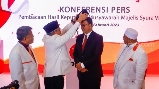 Presiden Partai Keadilan Sejahtera (PKS) Ahmad Syaikhu memakaikan peci secara simbolik kepada Anies Baswedan saat pengumuman deklarasi Calon Presiden 2024 dari PKS di Kantor DPP PKS, Jakarta Selatan, Kamis (23/2/2024). [Suara.com/Alfian Winanto]