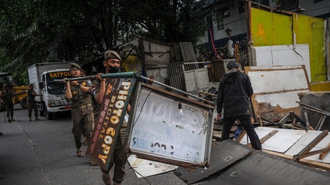 Petugas Satpol PP membersihkan material bangunan liar yang telah dirobohkan di Jalan Cijagra, Bandung, Jawa Barat, Kamis (23/2/2023). [ANTARA FOTO/Raisan Al Farisi]