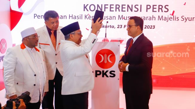 Presiden Partai Keadilan Sejahtera (PKS) Ahmad Syaikhu memakaikan peci secara simbolik kepada Anies Baswedan saat pengumuman deklarasi Calon Presiden 2024 dari PKS di Kantor DPP PKS, Jakarta Selatan, Kamis (23/2/2024). [Suara.com/Alfian Winanto]