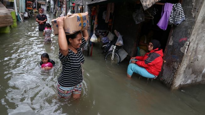 Sejumlah warga melintasi genangan banjir di Rawa Buaya, Cengkareng, Jakarta Barat, Senin (27/2/2023). [ANTARA FOTO/Prabanndaru Wahyuaji].