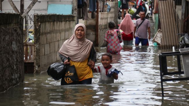 Sejumlah warga melintasi genangan banjir di Rawa Buaya, Cengkareng, Jakarta Barat, Senin (27/2/2023).  [ANTARA FOTO/Prabanndaru Wahyuaji].