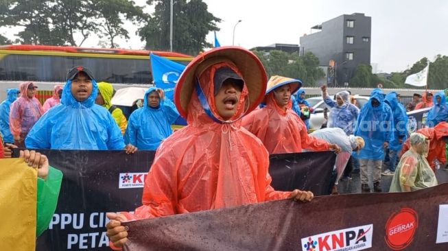 Massa buruh tolak Perppu Cipta Kerja meski bertahan berdemo di depan DPR, meski diguyur hujan. (Suara.com/Faqih)