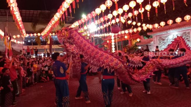 Pertunjukan naga di halaman Kelenteng See Hin Kiong Padang sehari jelang perayaan Imlek, Sabtu (21/1/2023). [Suara.com/Riki Chandra]