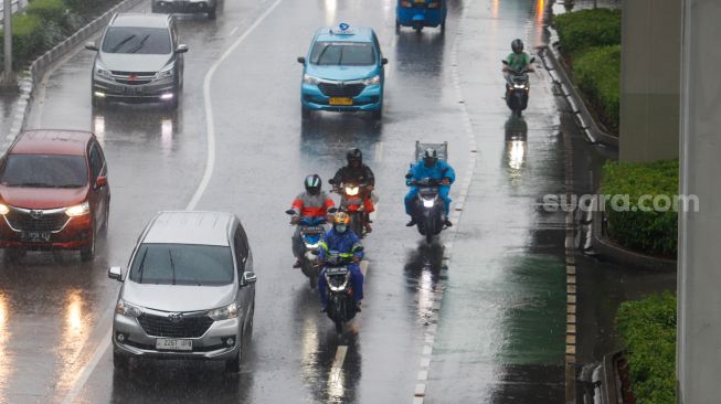 Pengendara motor nelintas saat hujan lebat di dalam Jalan Gatot Subroto, Jakarta, Kamis (3/3/2023). [Suara.com/Alfian Winanto]