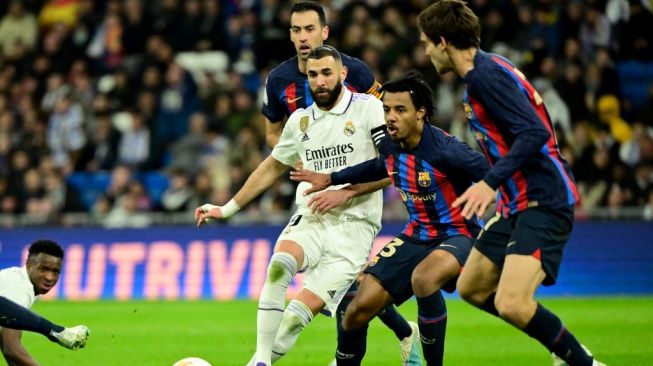 Real Madrid's France forward Karim Benzema (center) fights for the ball with Barcelona's French defender Jules Kounde during the first leg of the Copa del Rey semifinal match between Real Madrid vs Barcelona at the Santiago Bernabeu stadium in Madrid on March 2, 2023. JAVIER SORIANO / AFP.