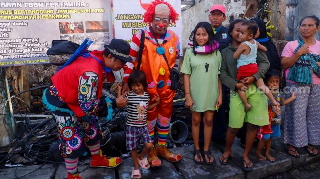 Sejumlah Badut yang tergabung dalam komunitas Aku Badut Indonesia (ABI) menghibur anak-anak di sekitar lokasi kebakaran Depo Pertamina Plumpang di Koja, Jakarta Utara, Rabu (8/3/2023). [Suara.com/Alfian Winanto]