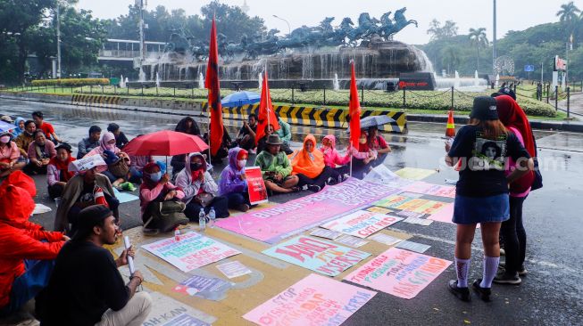 Para peserta melakukan aksi di sekitar Patung Kuda Arjuna Wiwaha, Jakarta Pusat, Rabu (8/3/2023). [Suara.com/Alfian Winanto]