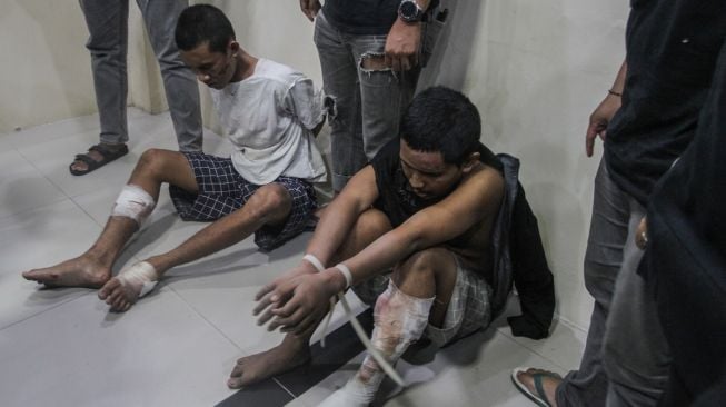 Petugas kepolisian berpakaian preman menjaga dua orang narapidana (napi) Pancareno Ramekencana (19) (kiri) dan Jihat Aji Nurmono (26) (kanan) yang berhasil ditangkap usai melarikan diri dari Lapas IIA Palangka Raya saat rilis penangkapan napi di RS Bhayangkara, Palangka Raya, Kalimantan Tengah, Selasa (7/3/2023). [ANTARA FOTO/Makna Zaezar].