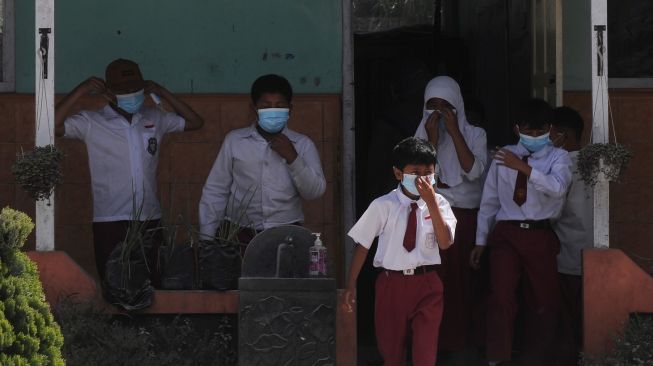 Sejumlah siswa menggunakan masker saat bermain di halaman sekolah saat jam istirahat pelajaran di Sekolah Dasar Negeri 2 Tlogolele, Selo, Boyolali, Jawa Tengah, Senin (13/3/2023). Aktivitas belajar mengajar masih berjalan meskipun aktivitas awan panas guguran Gunung Merapi masih terjadi, [ANTARA FOTO/Aloysius Jarot Nugroho].