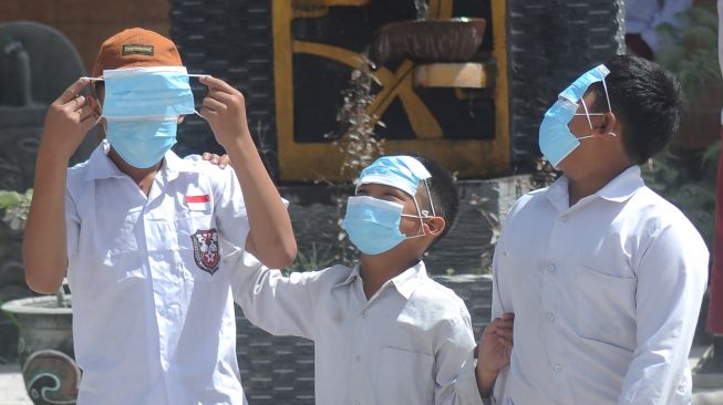 Sejumlah siswa menggunakan masker saat bermain di halaman sekolah saat jam istirahat pelajaran di Sekolah Dasar Negeri 2 Tlogolele, Selo, Boyolali, Jawa Tengah, Senin (13/3/2023). Aktivitas belajar mengajar masih berjalan meskipun aktivitas awan panas guguran Gunung Merapi masih terjadi, [ANTARA FOTO/Aloysius Jarot Nugroho].