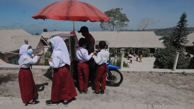 Sejumlah siswa menggunakan masker saat membeli makanan pada jam istirahat pelajaran di Sekolah Dasar Negeri 2 Tlogolele, Selo, Boyolali, Jawa Tengah, Senin (13/3/2023). Aktivitas belajar mengajar masih berjalan meskipun aktivitas awan panas guguran Gunung Merapi masih terjadi, [ANTARA FOTO/Aloysius Jarot Nugroho].