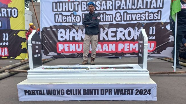 Massa tolak Perppu Cipta Kerja membawa baliho besar bergambar wajah 3 menteri di pemerintahan Joko Widodo, saat aksi di depan Gedung DPR Senayan pada Selasa (14/3/2023). [Suara.com/Faqih]