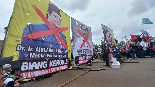 Massa Demo Tolak Perppu Cipta Kerja, Wajah Airlangga-Luhut Dicoret di Baliho Raksasa dan Menkeu Dibuat Bak Drakula