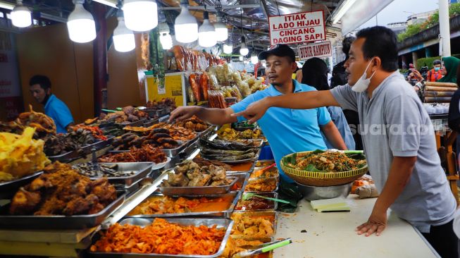 Pengunjung memilih menu berbuka puasa di Sentra kuliner Nasi Kapau di Jalan Kramat Raya, Senen, Jakarta Pusat, Jumat (24/3/2023). [Suara.com/Alfian Winanto]