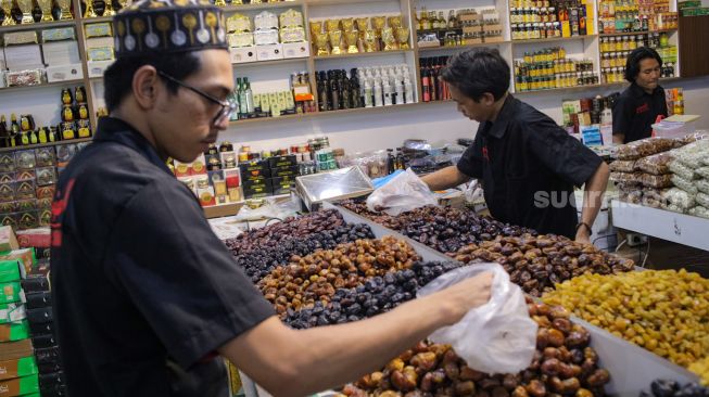 Pembeli memilih kurma yang dijual di kawasan Tanah Abang, Jakarta Pusat, Sabtu (25/3/2023). [Suara.com/Alfian Winanto]