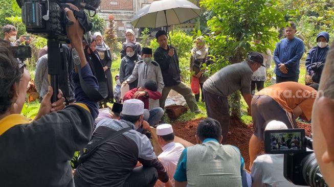 Adul memandangi proses pemakaman sang ibu, Umroni di TPU Kramat Pela, Kebayoran Baru, Jakarta Selatan, Sabtu (25/3/2023). Umroni meninggal dunia karena penyakit diabetes dan lambung di sebuah rumah sakit di Tangerang Selatan, Jumat (24/3/2023). [Adiyoga Priyambodo/Suara.com]