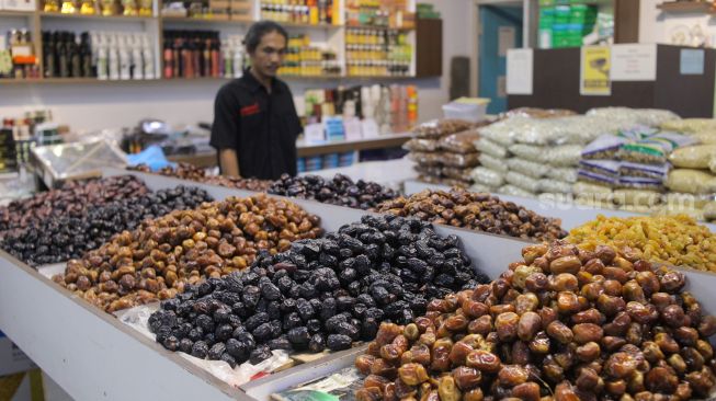 Pembeli memilih kurma yang dijual di kawasan Tanah Abang, Jakarta Pusat, Sabtu (25/3/2023). [Suara.com/Alfian Winanto]