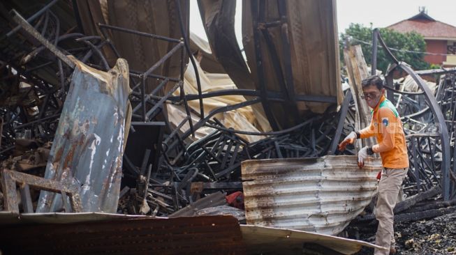 Petugas membersihkan sisa-sisa kebakaran di tempat penampungan hewan di Duren Sawit, Jakarta Timur, Senin (27/3/2023). [Suara.com/Alfian Winanto]