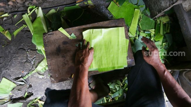 Pekerja menyelesaikan proses pembuatan lemang bambu di kawasan Senen, Jakarta, Jumat (31/3/2023). [Suara.com/Alfian Winanto]