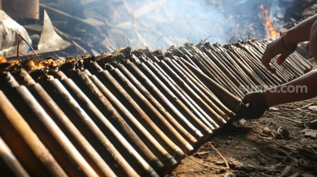 Pekerja menyelesaikan proses pembuatan lemang bambu di kawasan Senen, Jakarta, Jumat (31/3/2023). [Suara.com/Alfian Winanto]