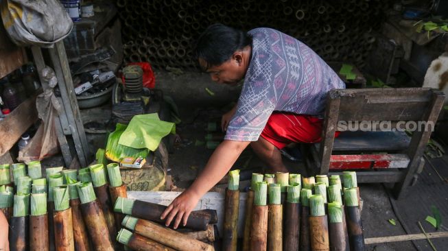 Pekerja menyelesaikan proses pembuatan lemang bambu di kawasan Senen, Jakarta, Jumat (31/3/2023). [Suara.com/Alfian Winanto]