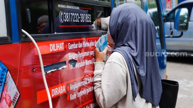 Warga menukarkan uang tunai baru di layanan kas keliling Bank Indonesia di Pasar Tebet Barat Jakarta Selatan, Selasa (4/4/2023). [Suara.com/Alfian Winanto]