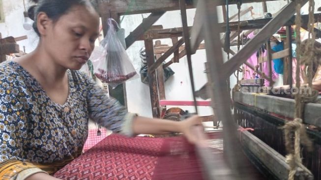 Kegiatan menenun sarung goyor di pabrik sarung cap Botol Terbang di Potrobangsan, Kota Magelang. (Suara.com/ Angga Haksoro Ardi).