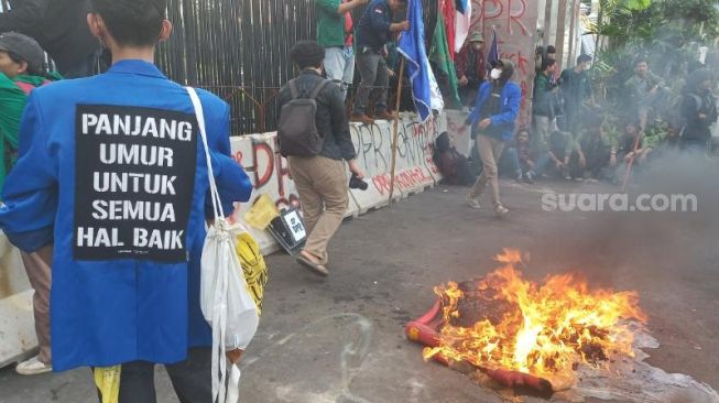 Aksi bakar ban massa mahasiwa saat demo tolak UU Cipta Kerja di depan Gedung DPR RI.  (Suara.com/Faqih)