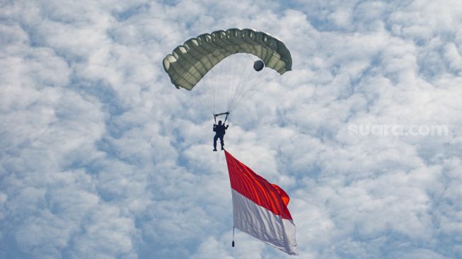 Penerjun mengibarkan bendera merah putih saat gladi HUT ke-77 TNI AU di Lanud Halim Perdanakusuma, Jakarta, Kamis (6/4/2023). [Suara.com/Alfian Winanto]