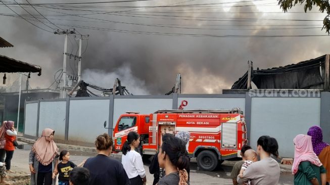 Petugas pemadam kebakaran masih memadamkan api di Gudang pengolahan biji plastik di Jalan Telkom, Sumur Batu, Bantargebang, Kota Bekasi, Sabtu (8/4). (Suara.com / Danan Arya)