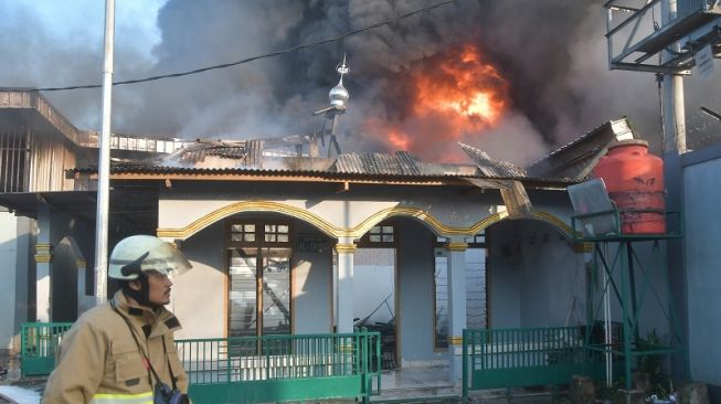 Petugas pemadam kebakaran melintas di samping Mushola Al-Zahro yang terbakar di Bantargebang, Bekasi, Jawa Barat, Sabtu (8/4/2023). [ANTARA FOTO/ Fakhri Hermansyah].