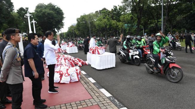 Presiden Joko Widodo atau Jokowi bersama Menteri BUMN Erick Thohir menyaksikan pembagian sembako untuk ojek online di depan Istana Merdeka, Jakarta, Kamis (13/4/2023). [Foto: Kris - Biro Pers Sekretariat Presiden]