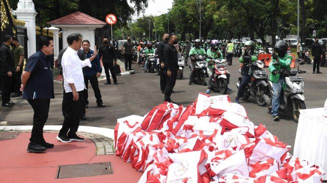 Presiden Joko Widodo atau Jokowi bersama Menteri BUMN Erick Thohir menyaksikan pembagian sembako untuk ojek online di depan Istana Merdeka, Jakarta, Kamis (13/4/2023). [Foto: Kris - Biro Pers Sekretariat Presiden]