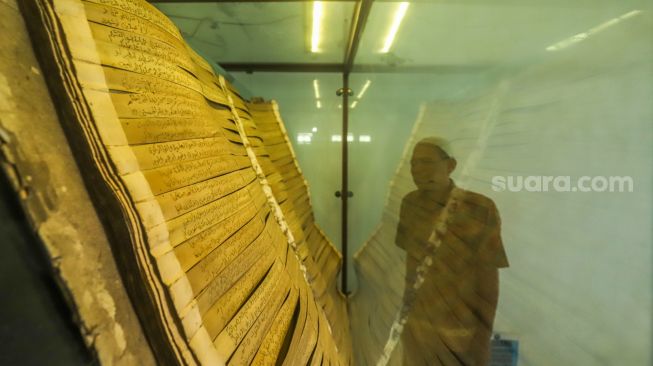 Warga melihat Alquran dari daun lontar yang tersimpan di Masjid Jami Matraman, Jakarta Timur, Rabu (13/4/2023). [Suara.com/Alfian Winanto]
