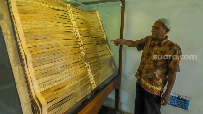 Warga melihat Alquran dari daun lontar yang tersimpan di Masjid Jami Matraman, Jakarta Timur, Rabu (13/4/2023). [Suara.com/Alfian Winanto]
