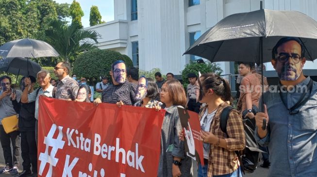 Aksi diam Haris Azhar dan Fatia jelang sidang kasus 'lord' Luhut di PN Jakarta Timur, Senin (17/4/2023). (Suara.com/Rakha)