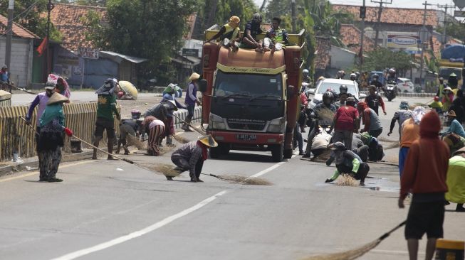 Sejumlah warga berebut mengambil uang sedekah dari pengendara yang melintas di Jembatan Sewo, Jalur Pantura Sukra Indramayu, Jawa Barat, Senin (17/4/2023). [ANTARA FOTO/Dedhez Anggara].