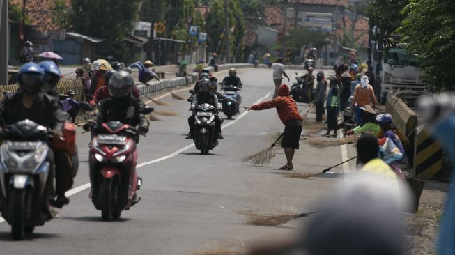 Sejumlah warga menunggu pengendara memberi sedekah dengan melempar uang di Jembatan Sewo, Jalur Pantura Sukra Indramayu, Jawa Barat, Senin (17/4/2023). [ANTARA FOTO/Dedhez Anggara].