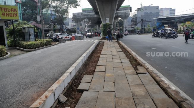 Pejalan kaki melintas di trotoar yang telah berubah fungsi menjadi jalan raya di Simpang Santa, Jakarta Selatan, Selasa (18/4/2023). [Suara.com/Alfian Winanto]