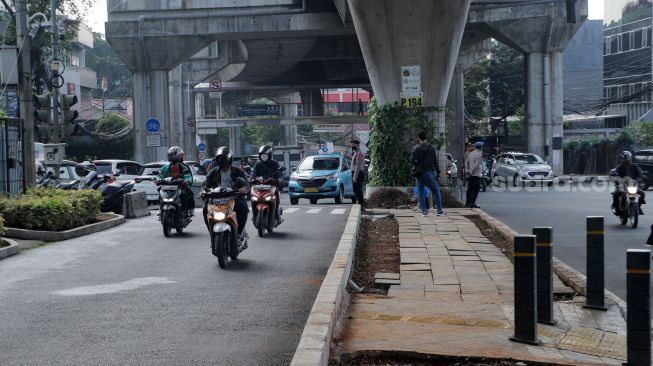 Kendaraan melintas di trotoar yang telah berubah fungsi menjadi jalan raya di Simpang Santa, Jakarta Selatan, Selasa (18/4/2023). [Suara.com/Alfian Winanto]