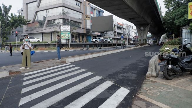 Pejalan kaki melintas di trotoar yang telah berubah fungsi menjadi jalan raya di Simpang Santa, Jakarta Selatan, Selasa (18/4/2023). [Suara.com/Alfian Winanto]