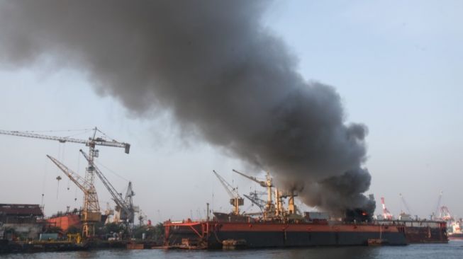 Petugas dengan menggunakan kapal tunda (tug boat) menyemprotkan air ke KM Anugerah Mandiri 8 yang terbakar di atas dok apung PT DOK dan Perkapalan Surabaya, Pelabuhan Tanjung Perak, Surabaya, Jawa Timur, Rabu (19/4/2023). [ANTARA FOTO/Didik Suhartono]