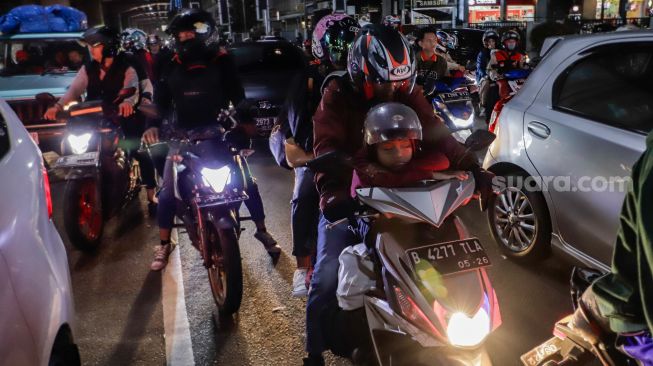 Pemudik yang menggunakan sepeda motor melintas di Jalan Raya Kalimalang, Jakarta Timur, Rabu (19/4/2023) malam. [Suara.com/Alfian Winanto]
