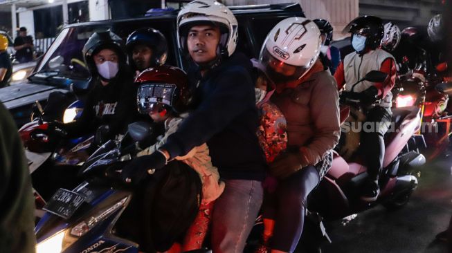 Pemudik yang menggunakan sepeda motor melintas di Jalan Raya Kalimalang, Jakarta Timur, Rabu (19/4/2023) malam. [Suara.com/Alfian Winanto]