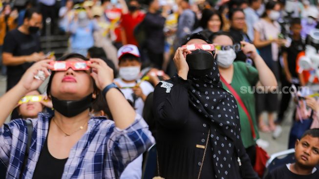 Warga mengamati fenomena Gerhana Matahari Hibrida di Taman Ismail Marzuki (TIM), Jakarta Pusat, Kamis (20/4/2023). [Suara.com/Alfian Winanto]