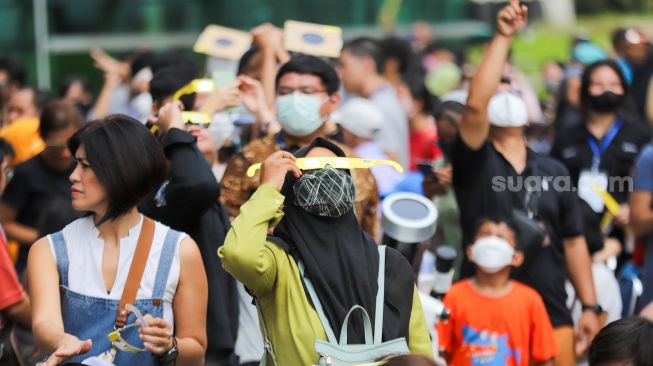 Warga mengamati fenomena Gerhana Matahari Hibrida di Taman Ismail Marzuki (TIM), Jakarta Pusat, Kamis (20/4/2023). [Suara.com/Alfian Winanto]