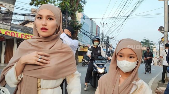 Ayu Ting Ting bersama putrinya, Bilqis Khumairah Razak menuju masjid untuk menjalani Salat Ied di kawasan Sukmajaya Depok, Jawa Barat, Sabtu (22/4/2023). [Adiyoga Priyambodo/Suara.com